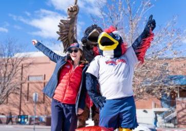 Rowdy the mascot and President Davidson pose for a photo with the Rowdy the Roadrunner statue in front of the Tivoli on a sunny afternoon in January 2024.